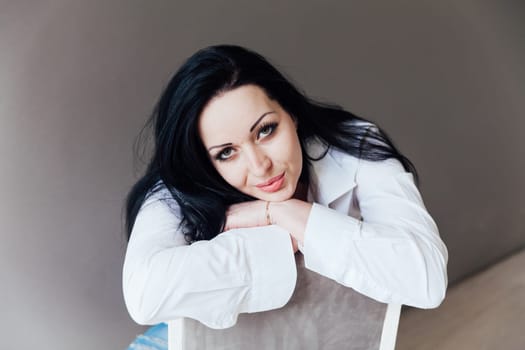Fashion brunette woman in white shirt portrait on gray background