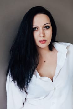 Fashion brunette woman in white shirt portrait on gray background