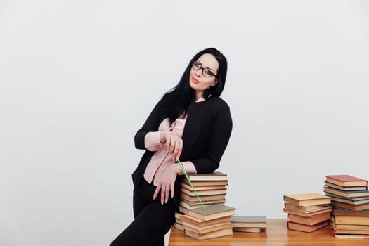 Woman teacher in suit and table with stacks of library educational books