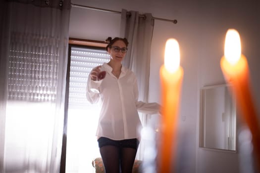 Woman wearing a white shirt holding a glass of wine celebrating hanukkah at home