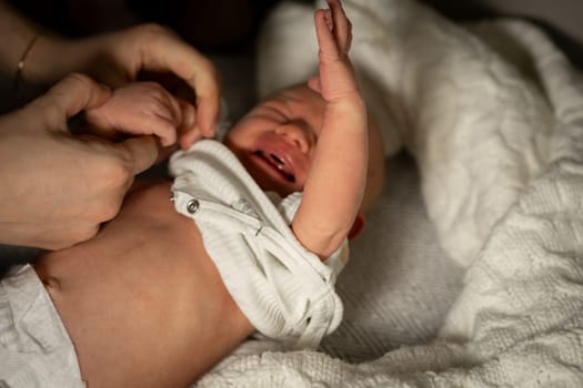 A mother tenderly changes her crying babys diaper in a warmly lit nursery. The atmosphere feels calm and intimate as they share this special moment.