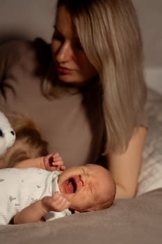 In a serene bedroom, a mother tenderly soothes her crying baby, holding a soft toy while creating a nurturing atmosphere in the evening light.