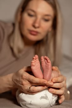 A mother lovingly supports her babys small feet, showcasing a tender connection in a warm and cozy environment during a serene afternoon.