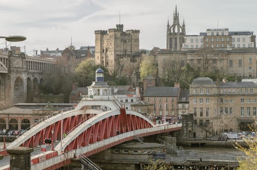 Newcastle, UK - Apr 11, 2025 - A view of The Iconic Swing bridge or Swing span bridge spanning spanning the River Tyne with historical buildings at the background in Newcastle Upon Tyne in the North East of England. The pedestrian bridge, use it as your Wallpaper, Poster and Space for text, Selective focus.