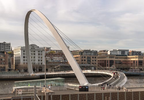 Newcastle, UK - Apr 11, 2025 - A view of The Iconic gateshead millennium bridge spanning the River Tyne with historical buildings at the background in Newcastle Upon Tyne in the North East of England. The pedestrian bridge, use it as your Wallpaper, Poster and Space for text, Selective focus.