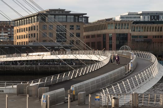 Newcastle, UK - Apr 11, 2025 - A view of The Iconic gateshead millennium bridge spanning the River Tyne with historical buildings at the background in Newcastle Upon Tyne in the North East of England. The pedestrian bridge, use it as your Wallpaper, Poster and Copy space, Selective focus.