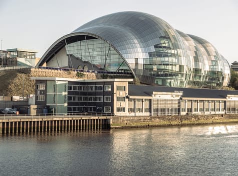 Newcastle, UK - Apr 11, 2025 - Architecture exterior view of The Glasshouse International Centre for Music or Sage Gateshead by the River Tyne before sunset. Modernist futuristic glass building, A concert venue and cultural centre in the city of Newcastle upon Tyne in Northumberland, use it as your Wallpaper, Poster and Copy space, Selective focus.