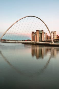 Newcastle, UK - Apr 13, 2025 - Beautiful scenery of The Iconic Gateshead millennium bridge spanning the River Tyne and Baltic flour mills with Magnificent sky in the background after sunset. The pedestrian bridge with reflection in the river, use it as your Wallpaper, Poster and Copy space, Selective focus.
