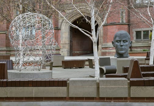 Newcastle, UK - Apr 14, 2025 - The Head in the Student Forum Space named Generation. are meant represent different eras of human and industrial production with Corten Steel head - Later advances in industry and Steel head - Resembles the modern digital age, Area at Newcastle University, use it as your Wallpaper, Poster and Space for text, Selective focus.