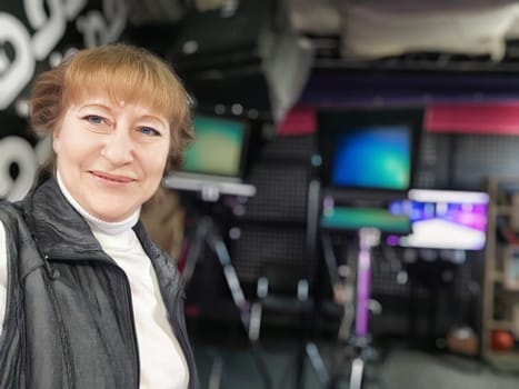 Blogger smiles at the camera in a stylish studio filled with equipment, ready to share her latest travel experiences.