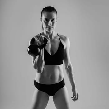 Fitness woman doing crossfit exercising with a kettle bell with muscular fit and slim body.