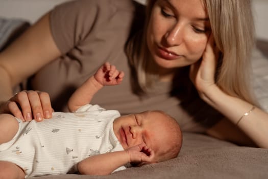 A mother lovingly interacts with her content baby while lying on a soft surface, creating a heartwarming atmosphere of care and bonding.