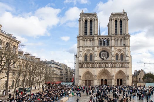 Paris, France - February 22nd 2025 : Notre-Dame de Paris and tourists in a queue waiting to see newly re-opened cathedral eager to see the restored building after reconstruction