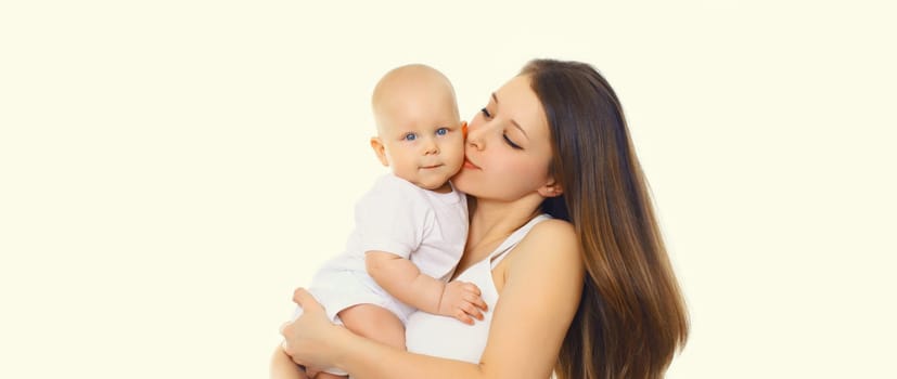 Portrait of happy mother kissing holding her baby, young mom and little child on white studio background