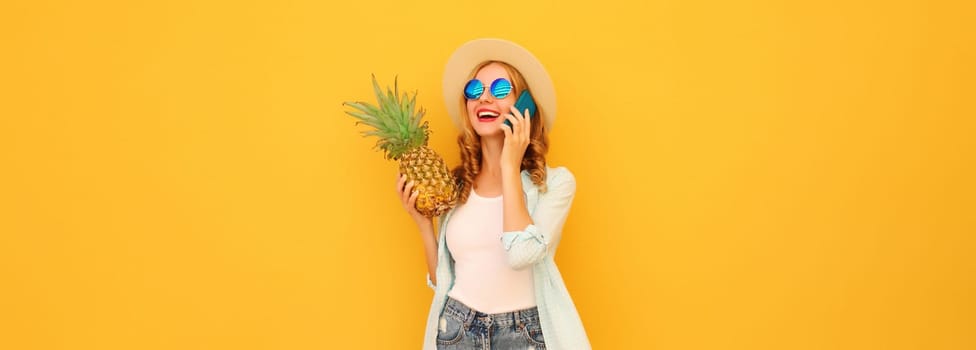 Summer vacation, happy joyful woman calling on phone with pineapple fruit in tourist hat, cheerful girl talking on the smartphone on yellow studio background