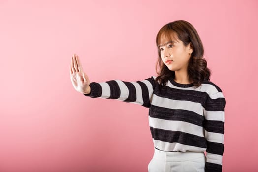 Asian portrait beautiful cute young woman teen smiling doing show stop sign gesture with palm of hand but happy face studio shot isolated on pink background, female doubt with copy space