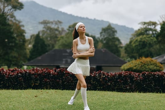 A confident female model in white athletic gear embodies grace and vitality against a backdrop of lush greenery, perfect for promoting active lifestyles and fitness