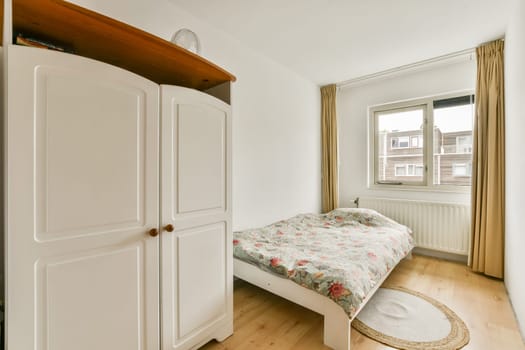 A bright and cozy modern bedroom featuring a comfortable bed, minimalist decor, wooden flooring, and ample natural light from the window.