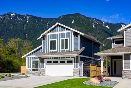 A perfect neighbourhood. Brand new house on the final stage of construction. Family house on snow mountain and blue sky background