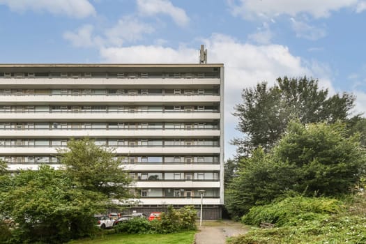 A contemporary residential structure with multiple floors, nestled amid lush greenery and trees, showcasing a balance of urban and natural elements.