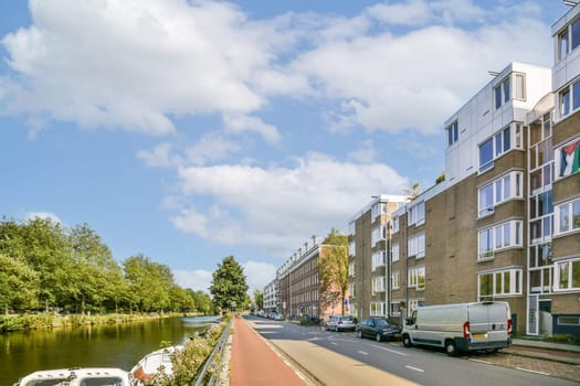 A picturesque view of an urban street lined with modern buildings, trees, and a serene canal, showcasing the beauty of city life.