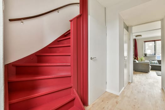 A modern interior showcasing a striking red spiral staircase leading to a cozy living space, complemented by soft lighting and contemporary decor.