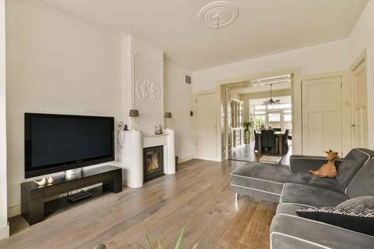 Spacious modern living room featuring a sleek TV setup, elegant furniture, and warm wooden flooring, creating a cozy and inviting atmosphere.