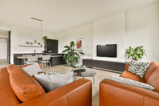 A stylish and contemporary living room featuring a cozy seating arrangement, greenery, and a minimalist aesthetic that promotes relaxation and comfort.