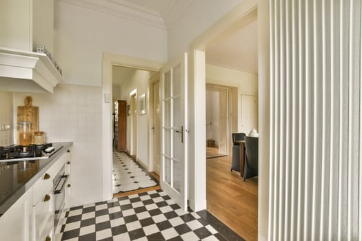 A stylish modern kitchen featuring white cabinetry, checkerboard flooring, and open-door access to a living area, creating a bright and inviting atmosphere.