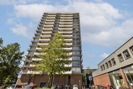 A contemporary multi-story apartment building featuring balconies and greenery in an urban setting, showcasing architectural design.