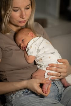 A mother gently holds her newborn baby in her arms while sitting comfortably at home, enjoying a serene and bonding experience in the afternoon.
