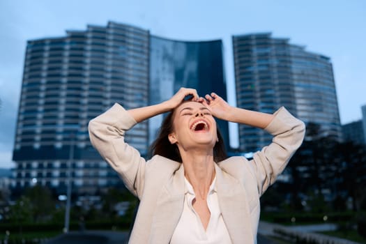 Happy woman in business attire expressing joy and success outdoors, surrounded by contemporary buildings, perfect for themes of empowerment and achievement.