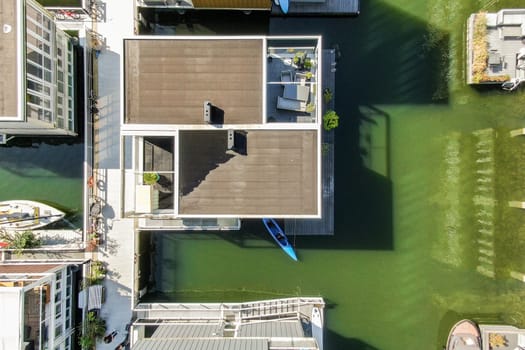 The image captures a bird's-eye view of contemporary waterfront houses surrounded by greenery and water, showcasing modern architecture and serene living.