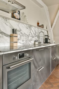 A sleek kitchen featuring elegant marble countertops, stainless steel appliances, and open shelving displaying kitchen essentials. A contemporary design adds to its charm.