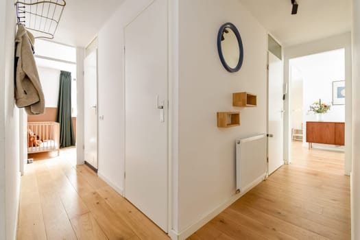 A stylish and minimalistic interior hallway featuring natural light, wooden flooring, and modern furniture elements. The space emphasizes simplicity and functionality.