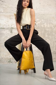 A fashionable model confidently showcasing a modern outfit while sporting a vibrant yellow backpack accessory