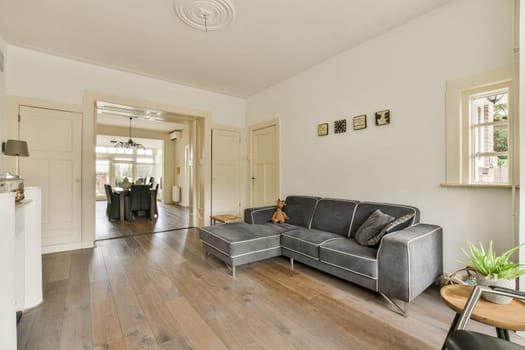 A contemporary styled living room featuring a gray sofa, wooden flooring, and a light color palette that enhances the spacious ambiance.