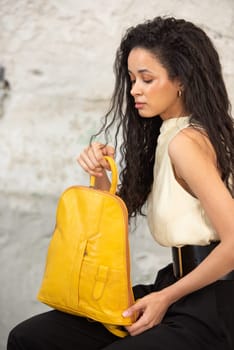 A fashionable model confidently showcasing a modern outfit while sporting a vibrant yellow backpack accessory