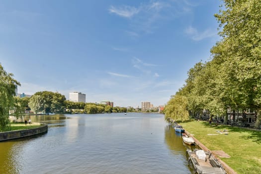 A tranquil riverside scene featuring lush greenery and modern buildings under a clear blue sky, ideal for relaxation and nature appreciation.