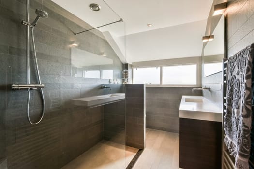 A sleek, contemporary bathroom featuring glass shower walls, minimalist fixtures, and stylish tile work, creating a luxurious and spacious environment.