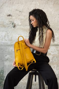 A fashionable model confidently showcasing a modern outfit while sporting a vibrant yellow backpack accessory