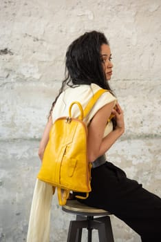 A fashionable model confidently showcasing a modern outfit while sporting a vibrant yellow backpack accessory
