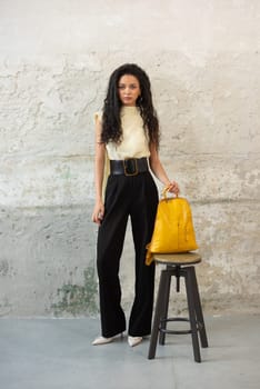 A fashionable model confidently showcasing a modern outfit while sporting a vibrant yellow backpack accessory