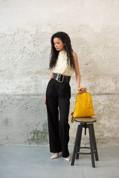 A fashionable model confidently showcasing a modern outfit while sporting a vibrant yellow backpack accessory