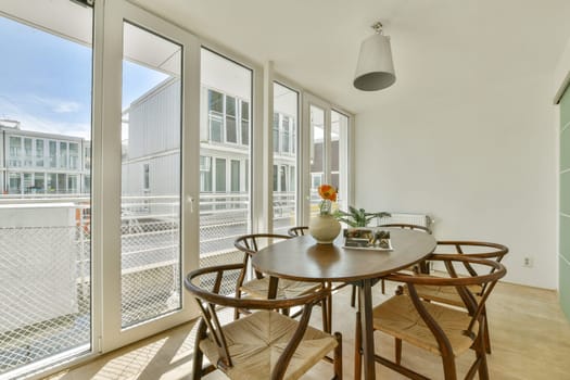 A bright and airy dining room featuring a round table set for four, surrounded by stylish chairs and large windows bringing in abundant natural light.