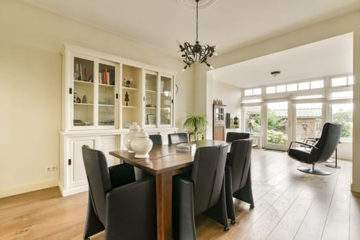 A stylish dining area featuring a wooden table, black chairs, and a bright window allowing natural light to enhance the ambiance, complemented by elegant decor.