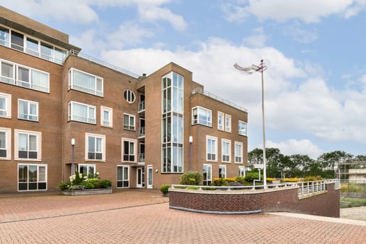 A contemporary brick building featuring large windows, geometric shapes, and landscaped grounds, showcasing modern architectural design.