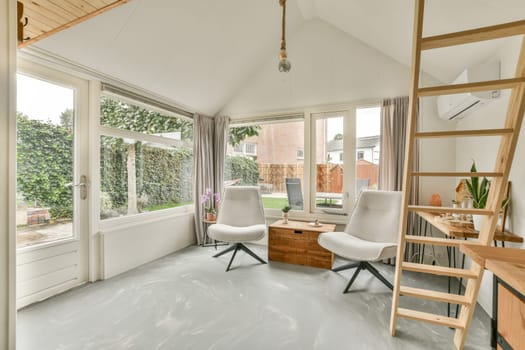 A stylish indoor living space featuring large windows that allow natural light to flood in, complemented by elegant furniture and a serene ambiance.