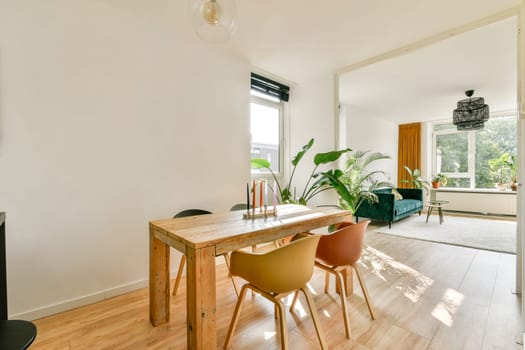 Stylish and modern interior featuring a wooden dining table, comfortable seating, and large windows bringing in natural light. A blend of functionality and elegance.