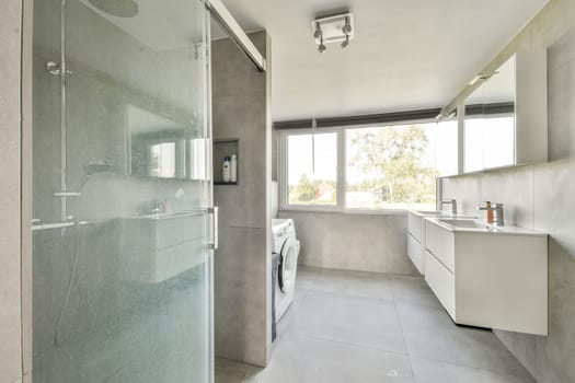 A stylish, modern bathroom featuring a clear glass shower, sleek vanity, and large windows that provide natural light.